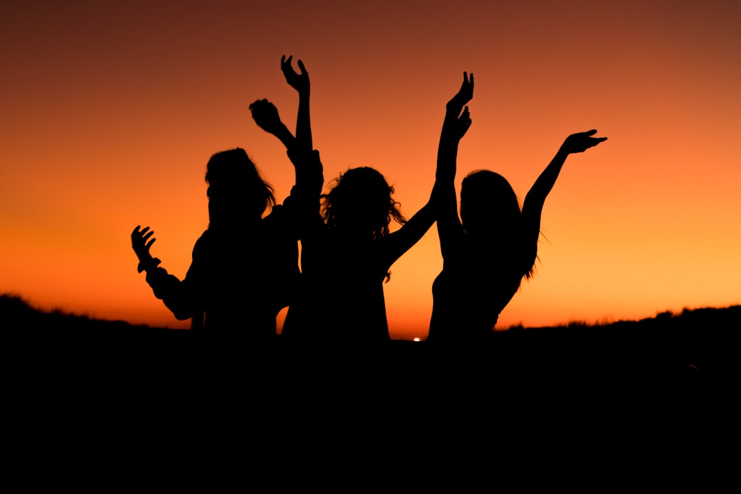 Photo by Levi Guzman silhouette of three woman with hands on the air while dancing during sunset